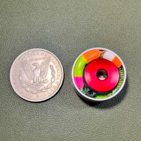 Miniature survival kit component shown next to a U.S. silver dollar for scale, highlighting its compact size and detailed construction.