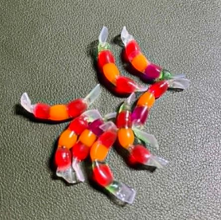 New salmon eggs cured and soaked in a proprietary garlic‑infused solution, shown glistening on a wood disc to highlight color, texture, and realism.